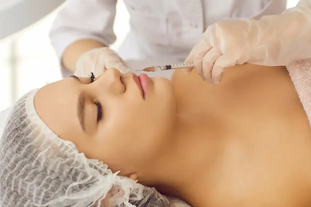 Ärztin führt eine präzise Lippenunterspritzung bei einer Patientin durch